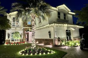 Christmas Light Installation Naples FL 8 Elegant home illuminated with Christmas light installation. A palm tree wrapped in lights stands in the yard, with festive lights outlining the roof and landscape, creating a warm, inviting glow.
